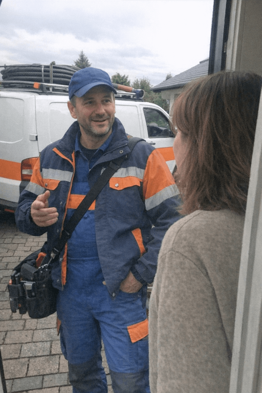 Freundlicher Techniker im Gespräch über Kanalreinigung Notdienst vor Ort beim Kunden